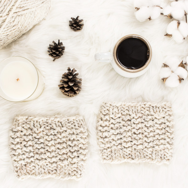 cozy scene of a cable knit boot cuffs on a faux fur blanket with coffee & a journal.
