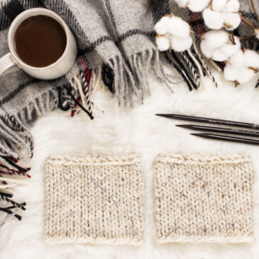 cozy scene of a cable knit boot cuffs on a faux fur blanket with coffee & knitting needles.