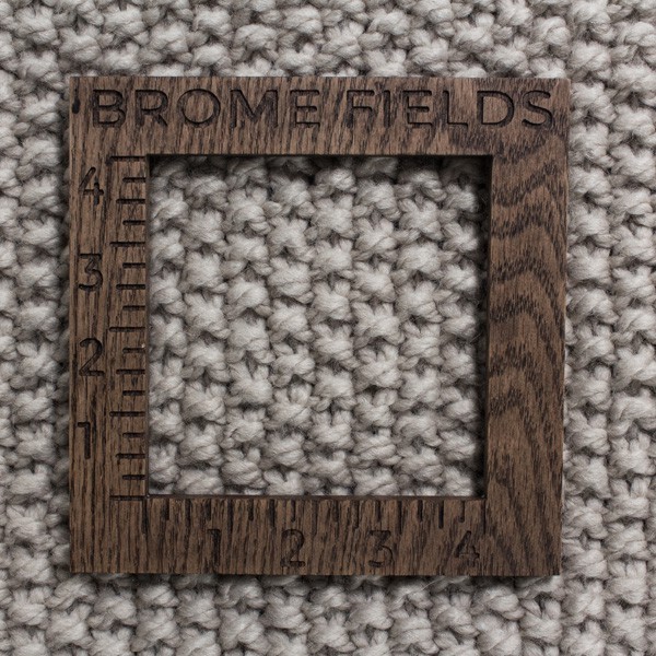 close-up of a knitted swatch with a wood gauge