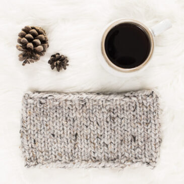 beginner knit headband on a fur blanket with pinecones & a coffee