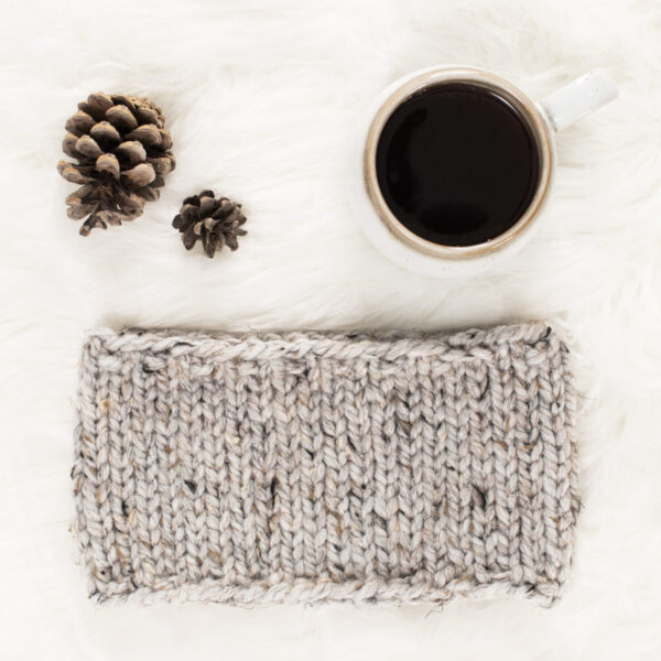 beginner knit headband on a fur blanket with pinecones & a coffee