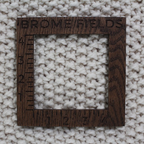 close-up of a knitted swatch with a wood gauge