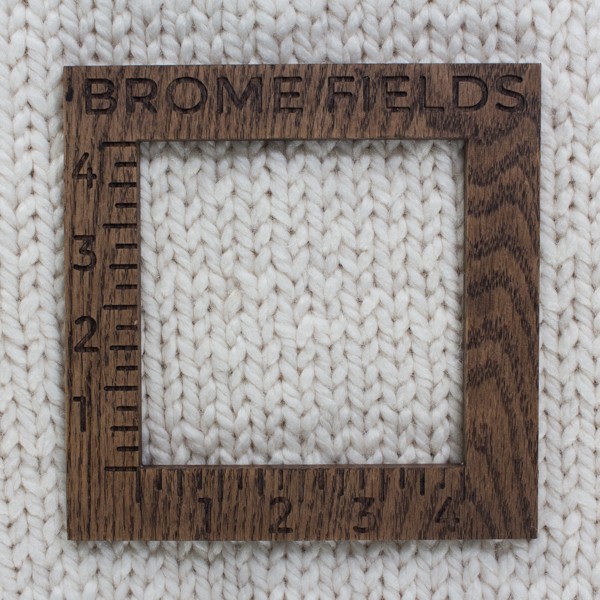 close-up of a knitted swatch with a wood gauge