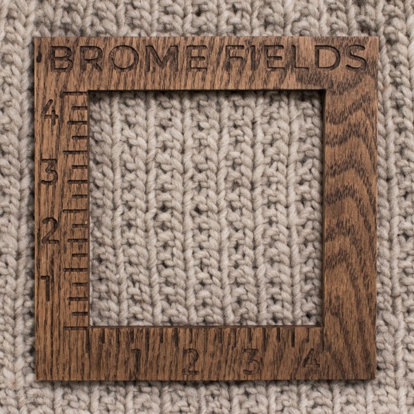 close-up of a knitted swatch with a wood gauge