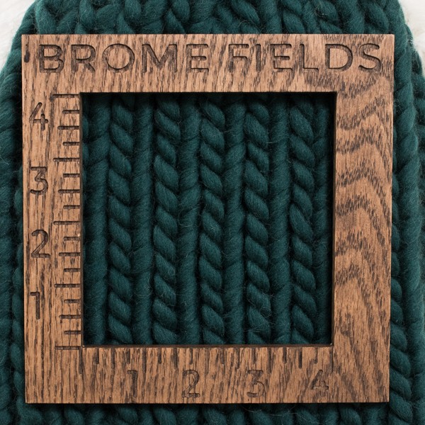close-up of a knitted swatch with a wood gauge