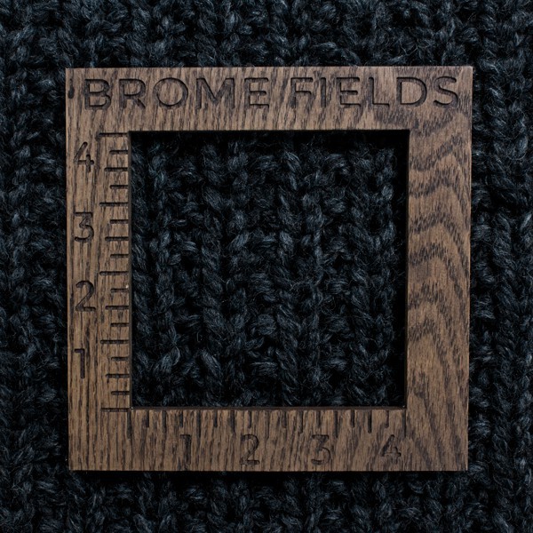 close-up of a knitted swatch with a wood gauge