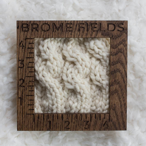 close-up of a knitted swatch with a wood gauge
