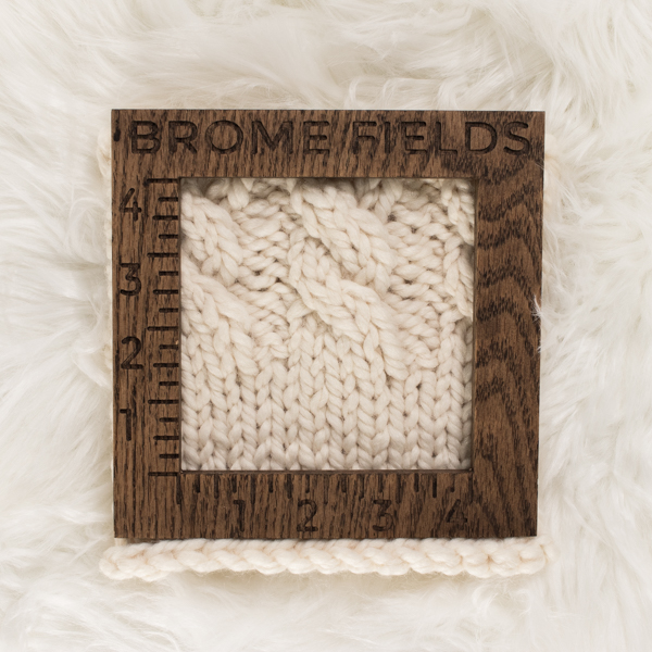 close-up of a knitted swatch with a wood gauge