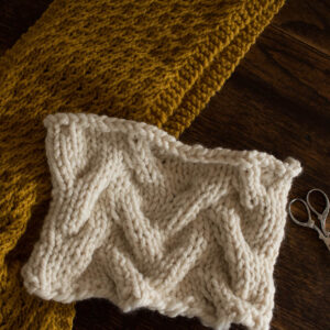 Swatch of the Sand Tracks Cable Knitting Stitch Pattern on a wood table.