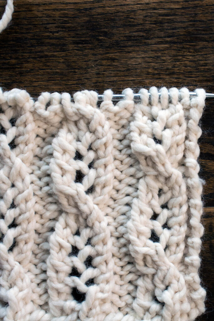 Swatch of the Cable Lace Knitting Stitch Pattern on a wood table.