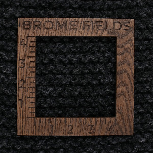 close-up of a knitted swatch with a wood gauge