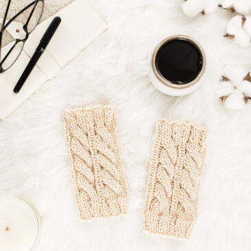 cozy scene of a cable knit leg warmers on a faux fur blanket with coffee & a journal.