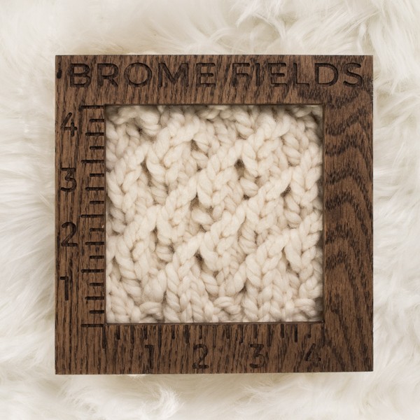 close-up of a knitted swatch with a wood gauge