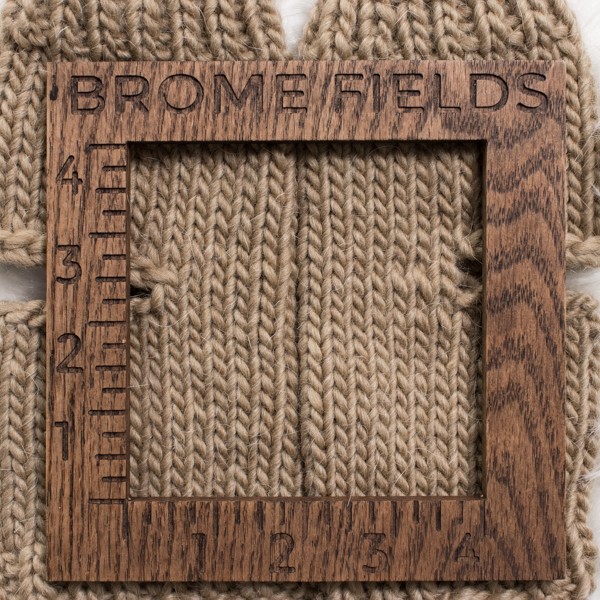 close-up of a knitted swatch with a wood gauge