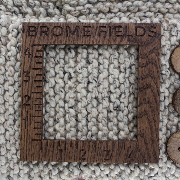 close-up of a knitted swatch with a wood gauge