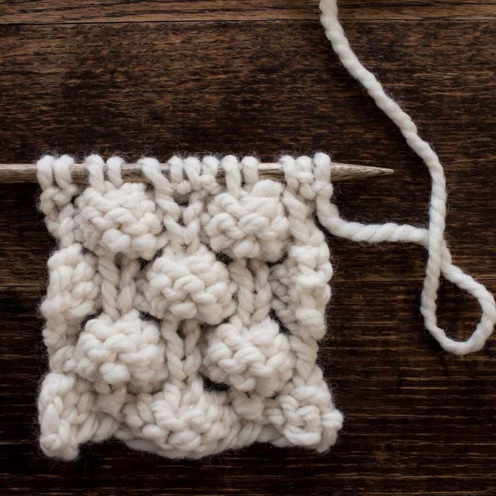 knitted swatch of a bobble stitch on a wood table