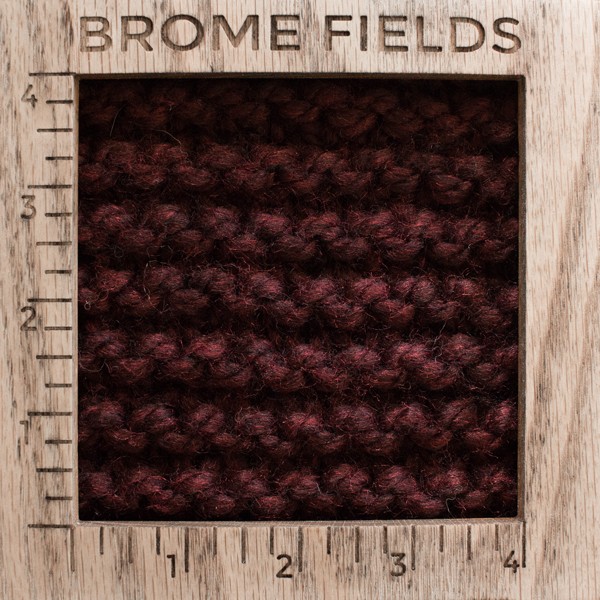 close-up of a knitted swatch with a wood gauge