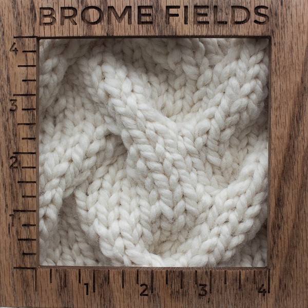 close-up of a knitted swatch with a wood gauge