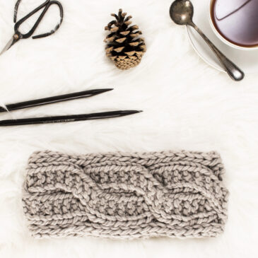 cable knit headband on a fur blanket with knitting needles & a coffee