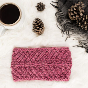 pic of a knitted chevron headband on a faux fur blanket with coffee & pine cones.