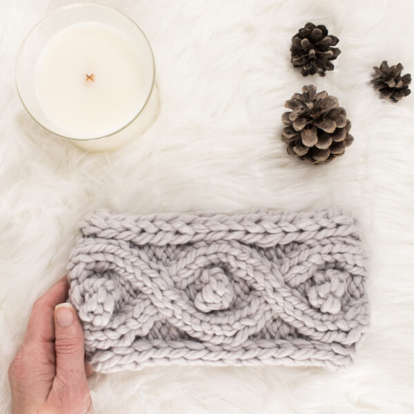 pic of a knitted cable headband with bobbles on a faux fur blanket