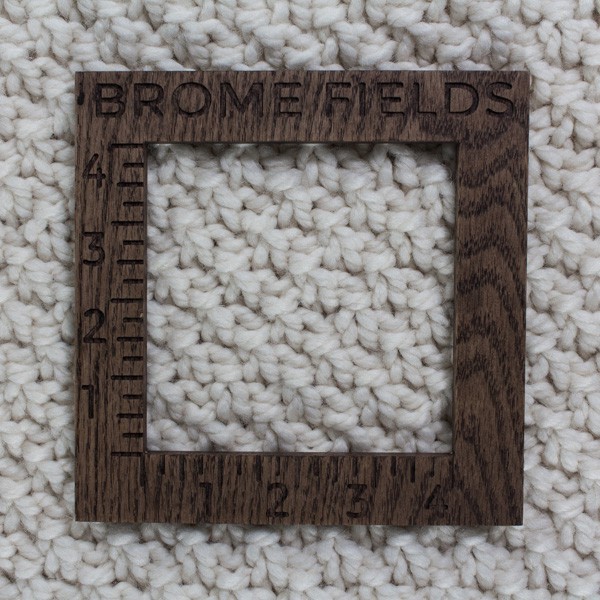 close-up of a knitted swatch with a wood gauge