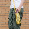 Knitted yellow water bottle sling in a hydro flask on a model.
