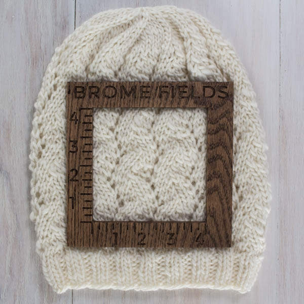 close-up of a knitted swatch with a wood gauge