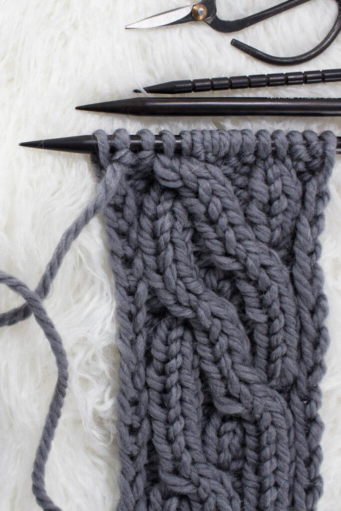 Swatch of the Crossing Pathways Cable Knit Stitch on a fur blanket.