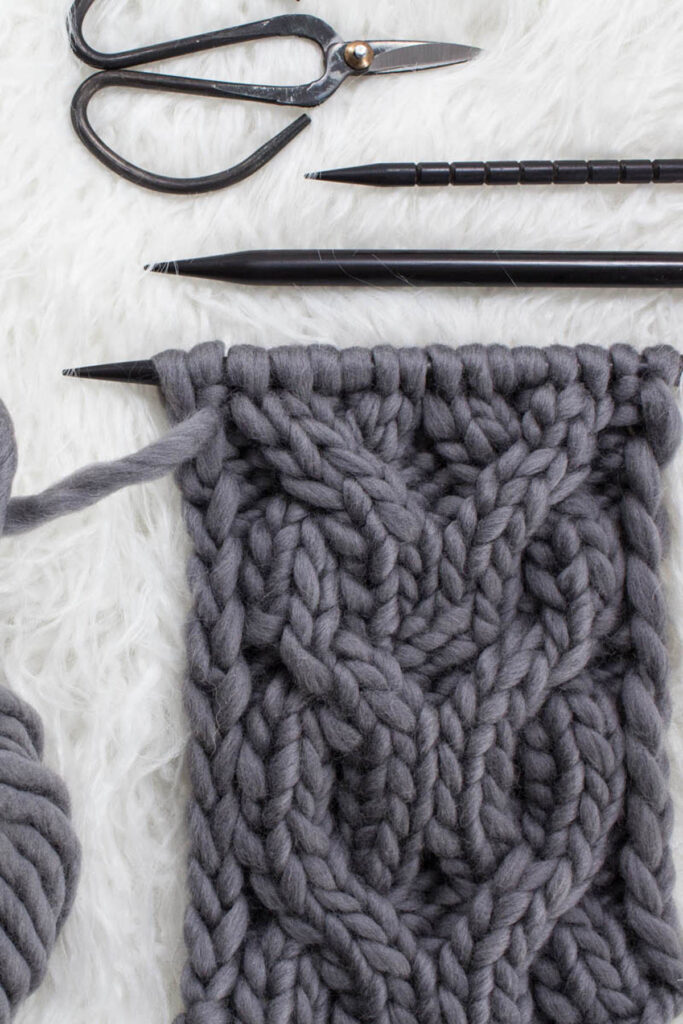 Swatch of the Double-O Cable Knit Stitch on a fur blanket.