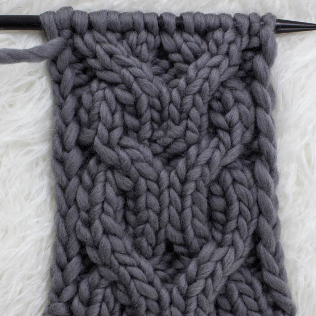 Swatch of the Double-O Cable Knit Stitch on a fur blanket.