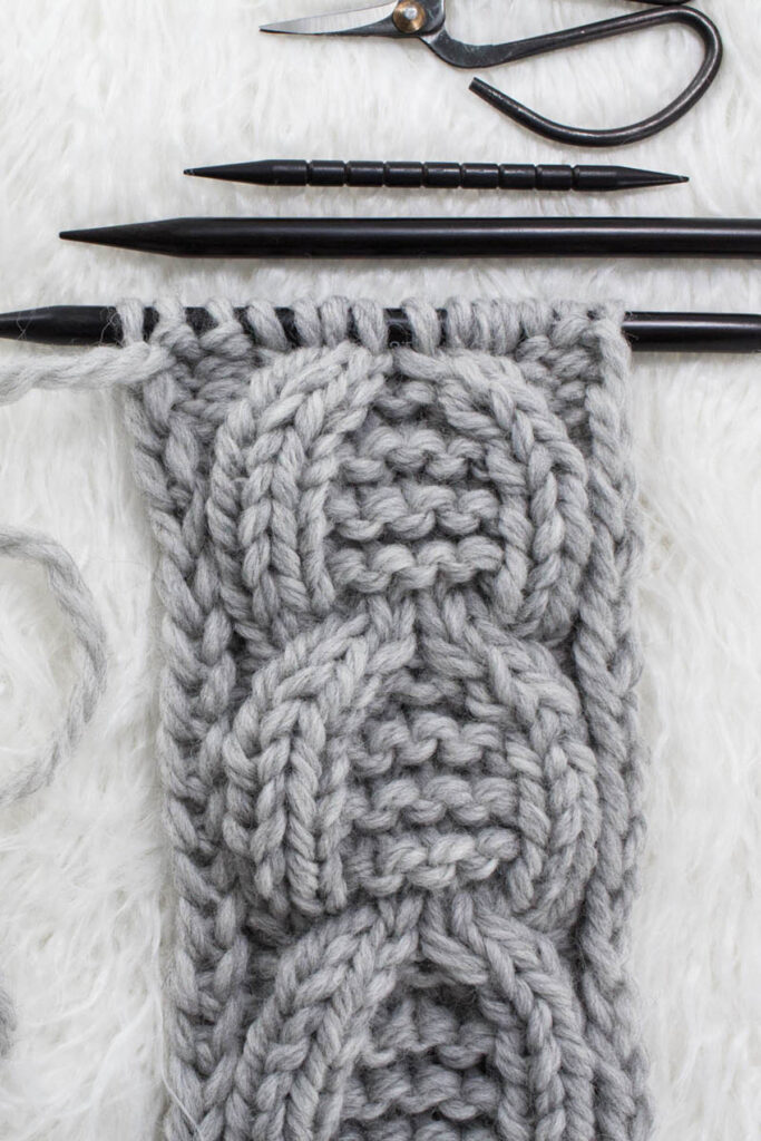 Swatch of the Garter Horseshoe Cable Knit Stitch on a fur blanket.