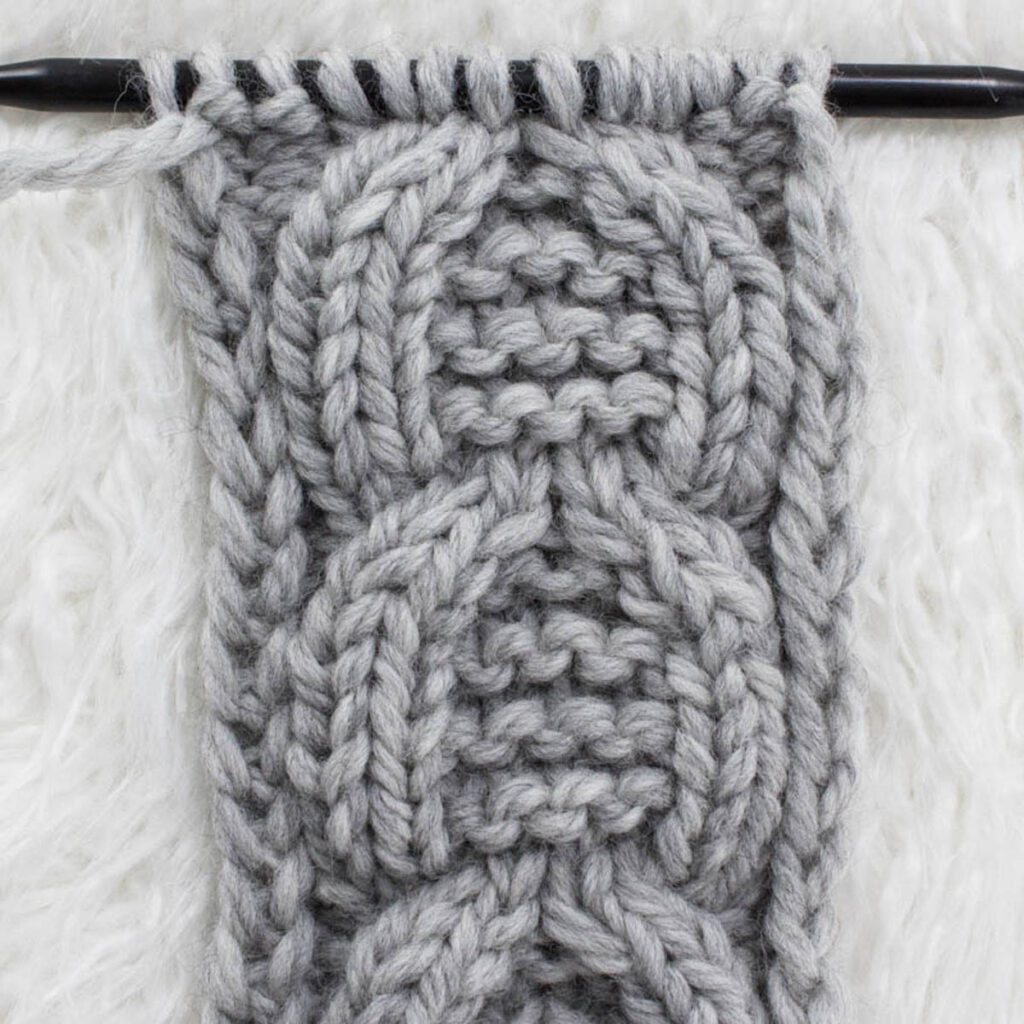 Swatch of the Garter Horseshoe Cable Knit Stitch on a fur blanket.