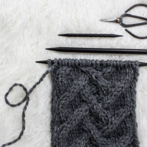 swatch of lattice herringbone cable knit stitch on a fur blanket