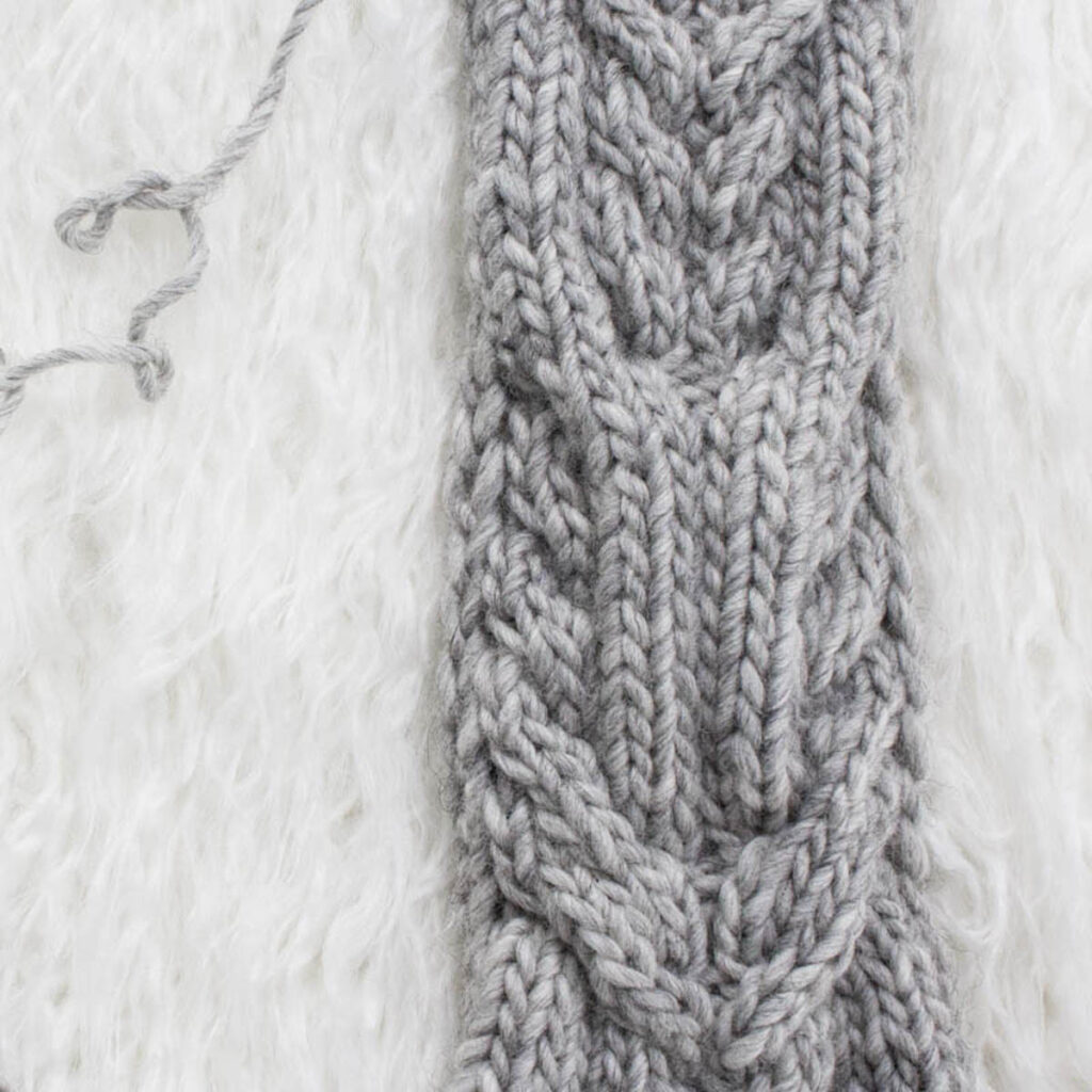 Swatch of the Interlaced Cables Cable Knit Stitch on a fur blanket.