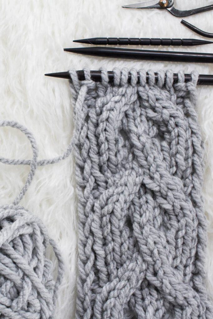 Swatch of the Twisted Eyelet Cable Knit Stitch on a fur blanket.