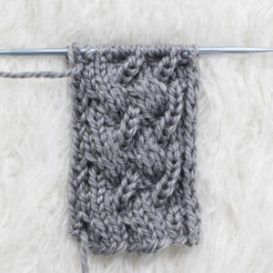Swatch of the Uneven Cable Knit Stitch on a fur blanket.
