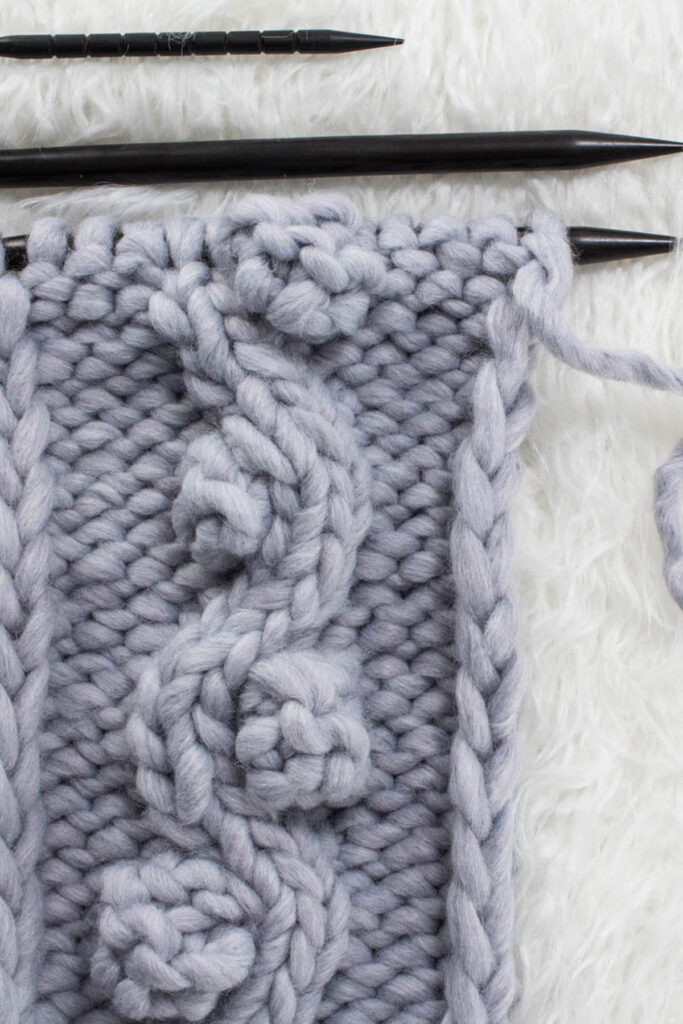 Swatch of the Wavy Bobble Cable Knit Stitch on a fur blanket.