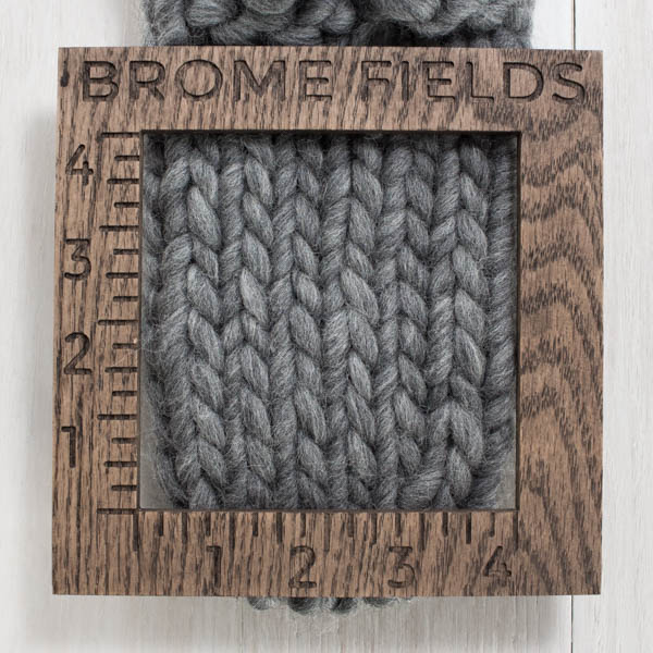 close-up of a knitted swatch with a wood gauge