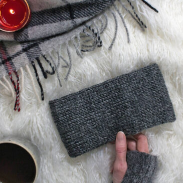 Classic stockinette headband knitting pattern on a flannel blanket with a cup of coffee & a candle.