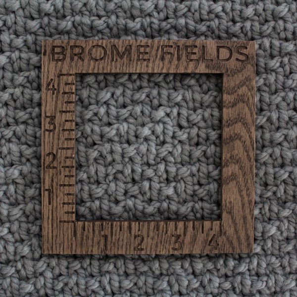 close-up of a knitted swatch with a wood gauge