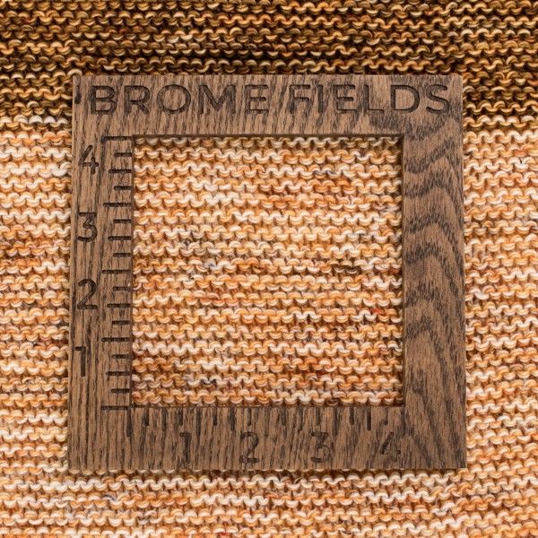 close-up of a knitted swatch with a wood gauge