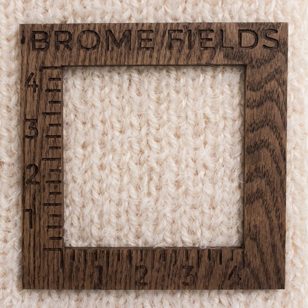 close-up of a knitted swatch with a wood gauge