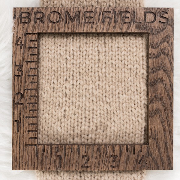 close-up of a knitted swatch with a wood gauge
