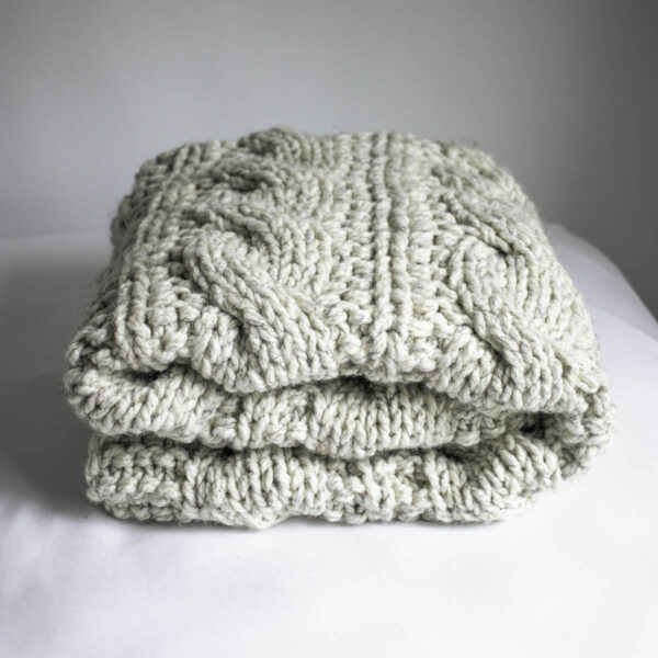 Close-up of A Beautiful Journey Blanket in super bulky yarn, showing the chunky and cozy texture of the cable knit stitch.