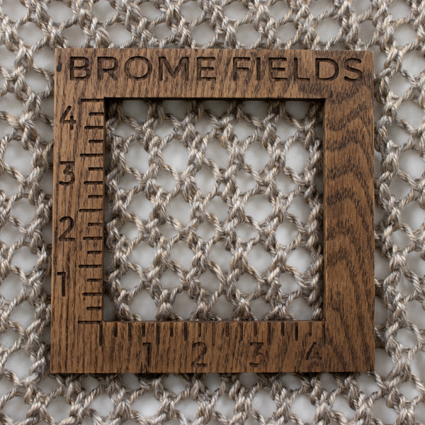knitted swatch with a wood gauge
