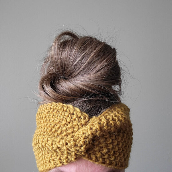 model wearing a chunky seed stitch headband with a messy bun