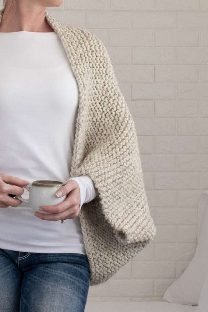 model wearing a chunky oversized shrug holding a coffee cup