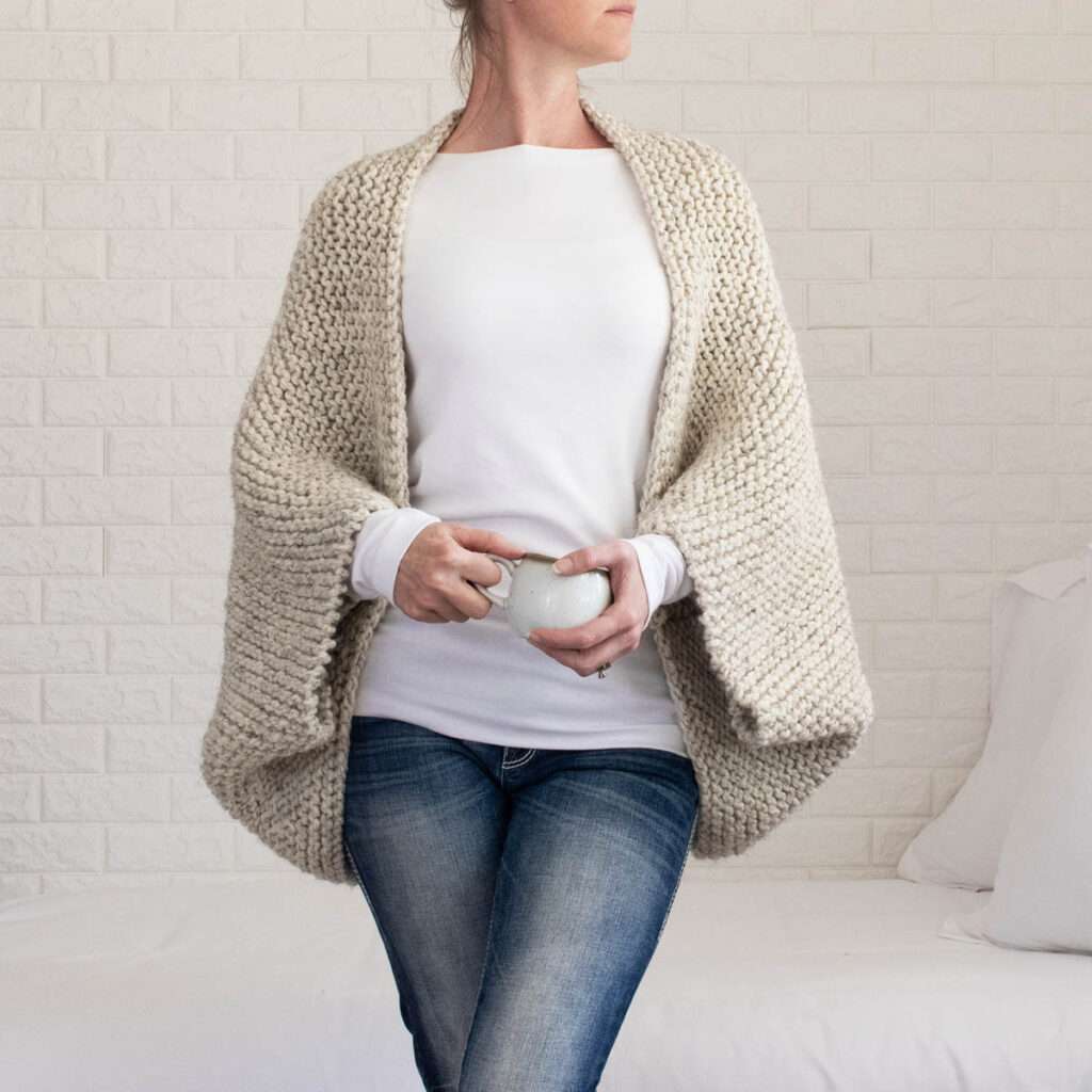 model wearing a chunky oversized shrug holding a coffee cup