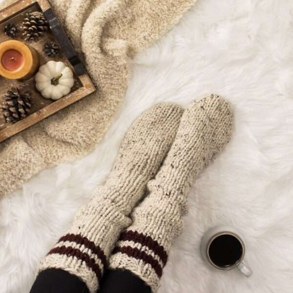 a cozy setting with chunky knit socks, coffee, candles and a blanket.